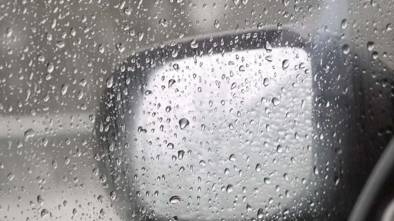 水滴落在车窗玻璃上。雨滴落在蓝色的窗户上。雨点落在雨天。下雨，慢镜头，特写视频素材