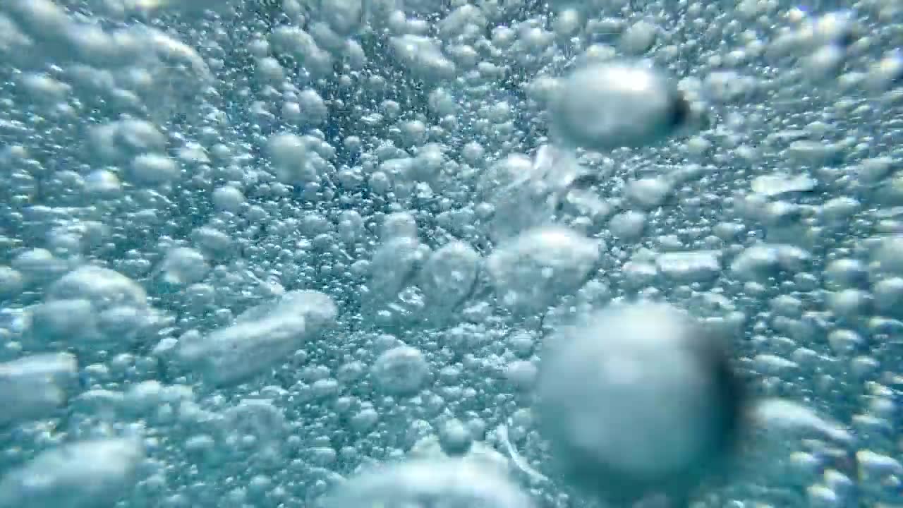 一个十几岁的男孩在一个有泡泡的游泳池里玩耍。——慢动作视频素材画面1
