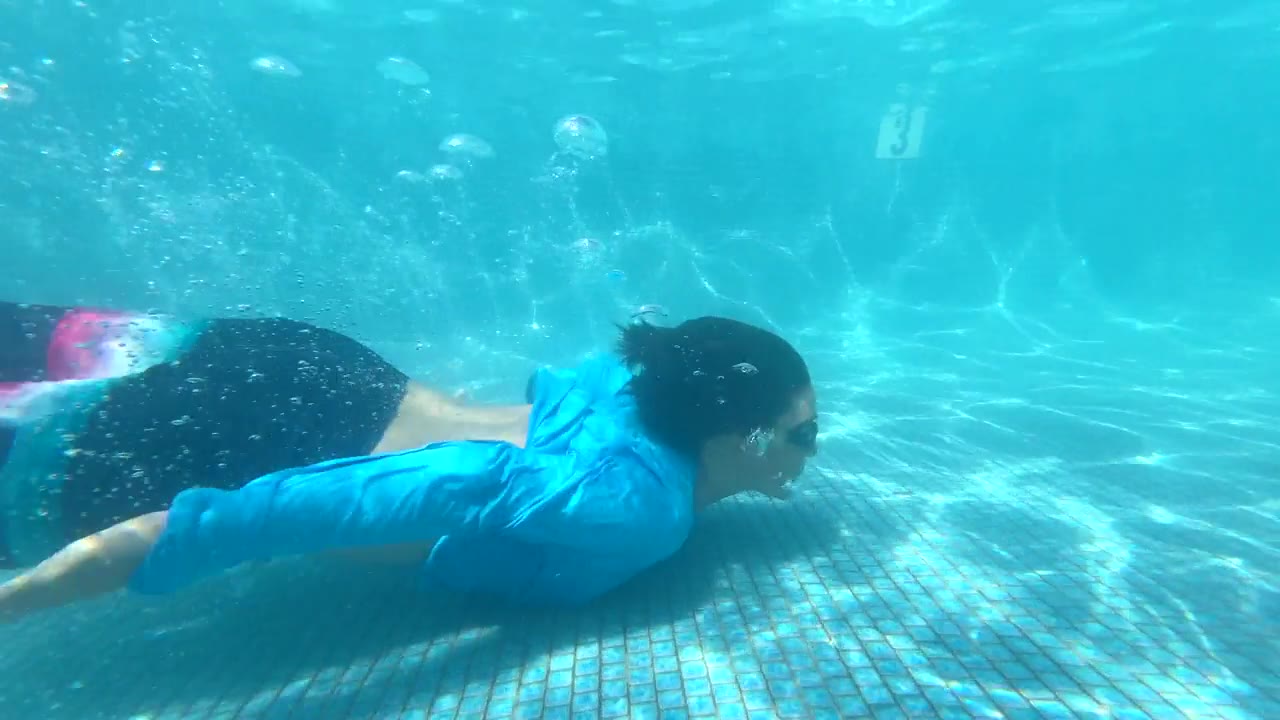 图为，一名十几岁的男孩在酒店度假区的游泳池里游泳和玩耍时面带微笑。——慢动作视频素材画面1