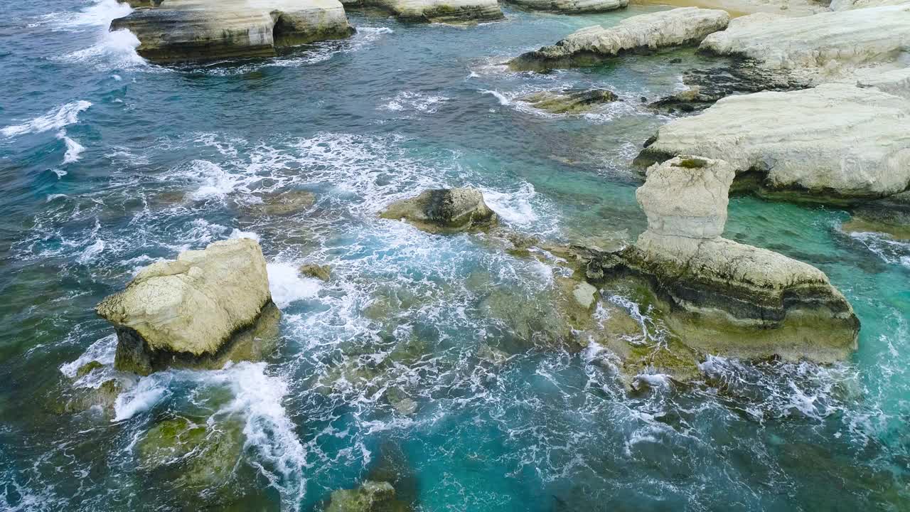 鸟瞰图的波浪打破岩石在蓝色的海洋，海浪在美丽的海滩上，无人机4k拍摄，海洋撞击孤独的山岩石，旅游目的地，度假和娱乐视频素材