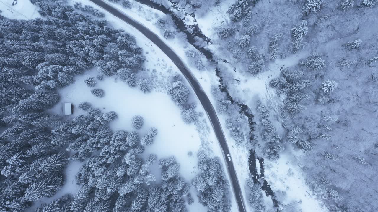 4K空中俯视图无人机拍摄的冬季森林景观森林覆盖的雪在塔特拉山脉与乡村道路和移动的汽车。交通和自然概念素材。视频素材