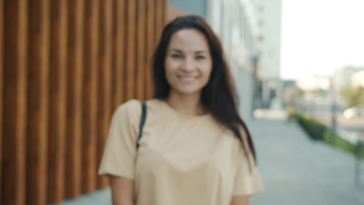 一个无忧无虑的年轻女孩在夏天站在城市的街道上视频素材