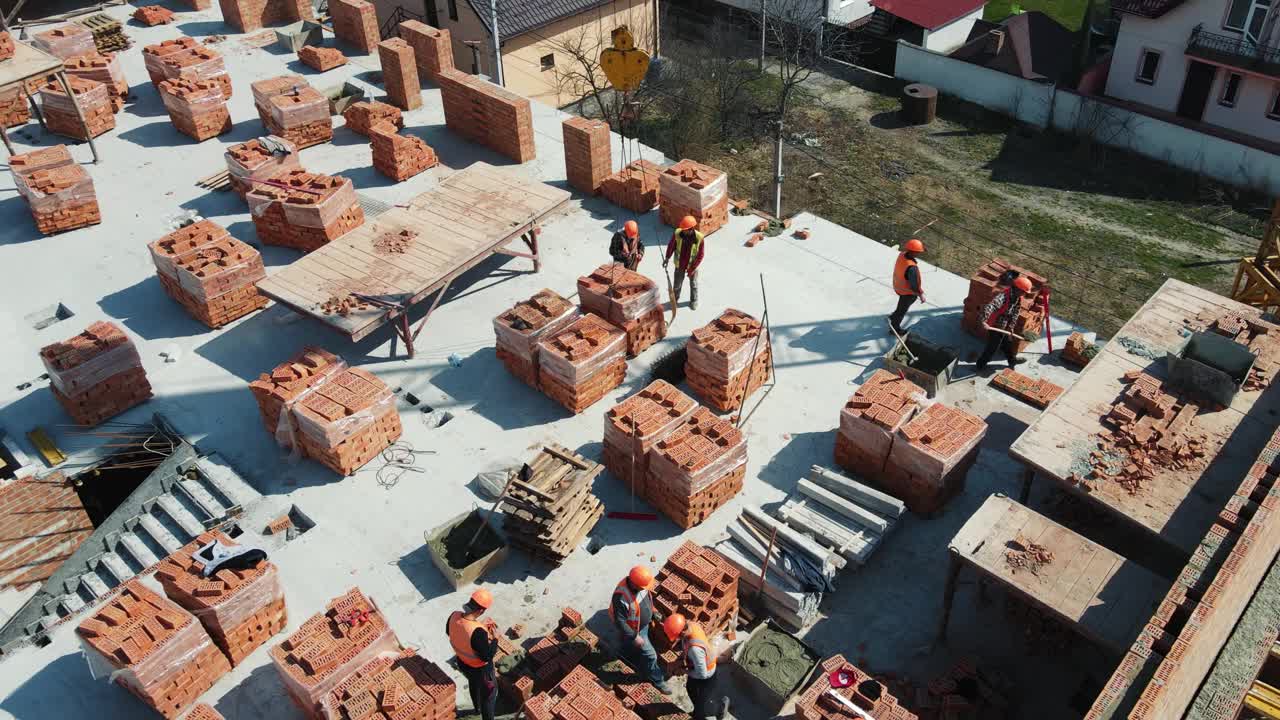 屋顶鸟瞰图红砖房子的建造。建筑工人们正在建造一座多层砖房视频素材