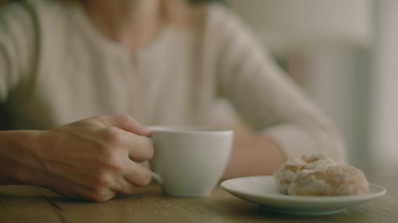 一个女人坐在家里一个大窗户旁边的桌子旁视频素材