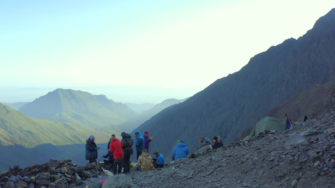 登山者在下午长途跋涉之前，会在山上的营地里吃点东西。视频素材