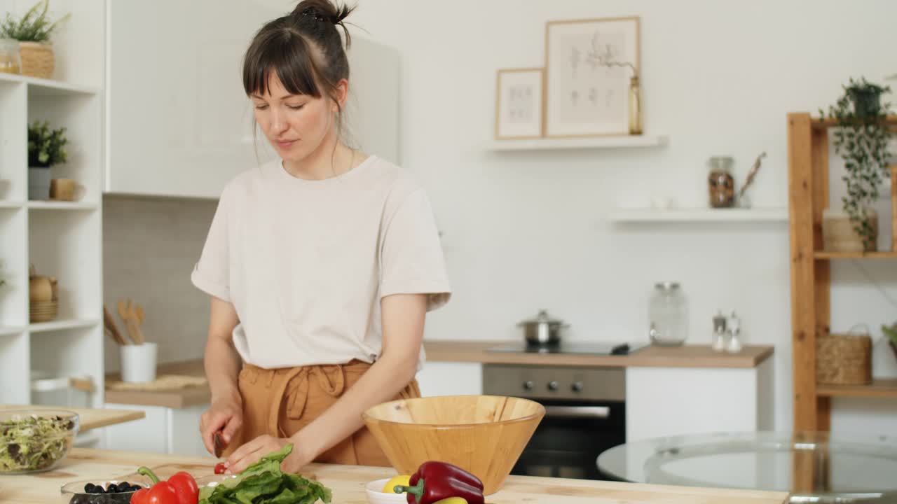 年轻女子在厨房里做沙拉视频素材