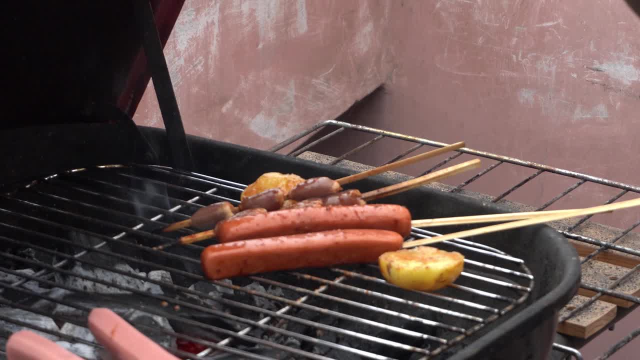 特写镜头:白天，在4k的屋顶烧烤架上，把各种各样的香肠和牛肉心放在木棒上，再加上玉米皮视频素材