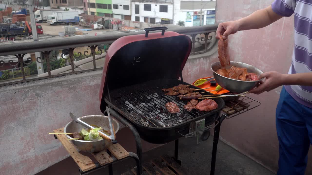 特写镜头:白天在4k的屋顶上，用手把香肠调味料倒在烧炭的烤架上视频素材