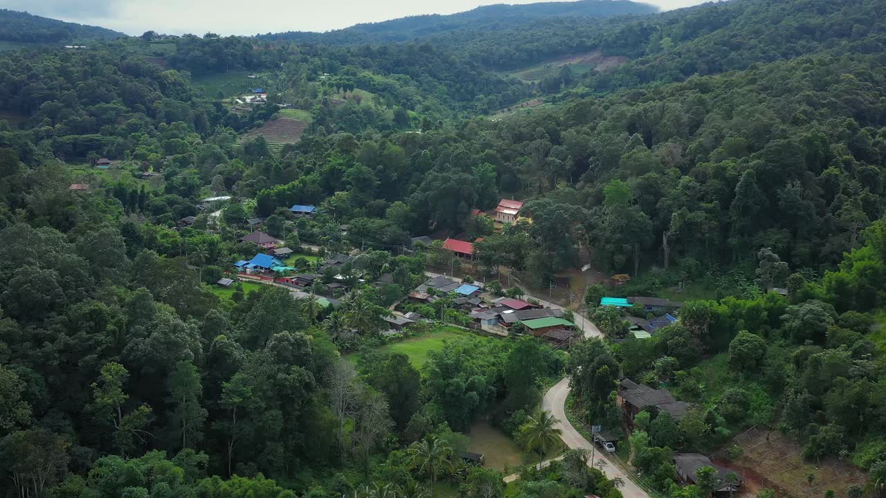 鸟瞰被群山环绕的村庄。无人机在泰国北部山区环绕的乡村城市上空飞行。视频素材