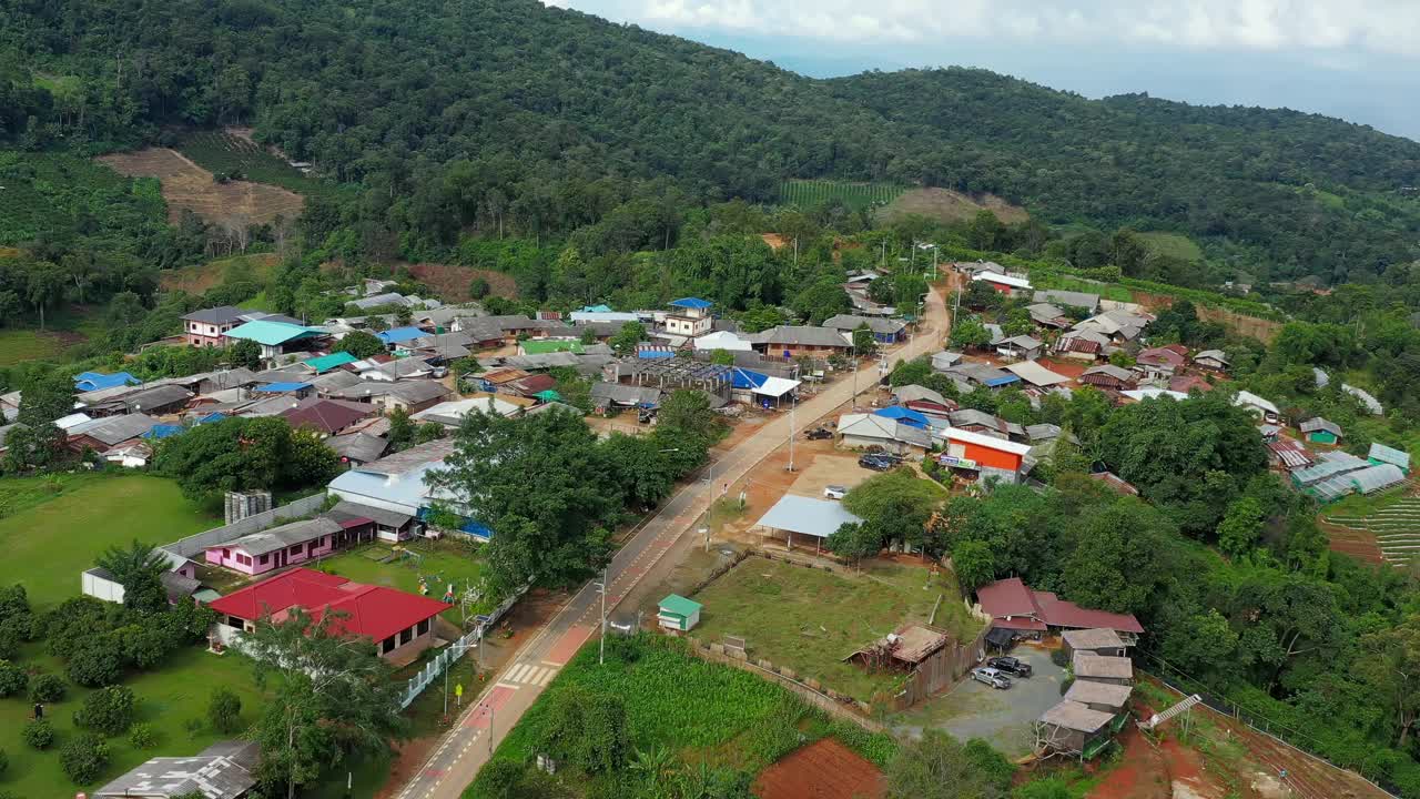 鸟瞰被群山环绕的村庄。无人机在泰国北部山区环绕的乡村城市上空飞行。视频素材