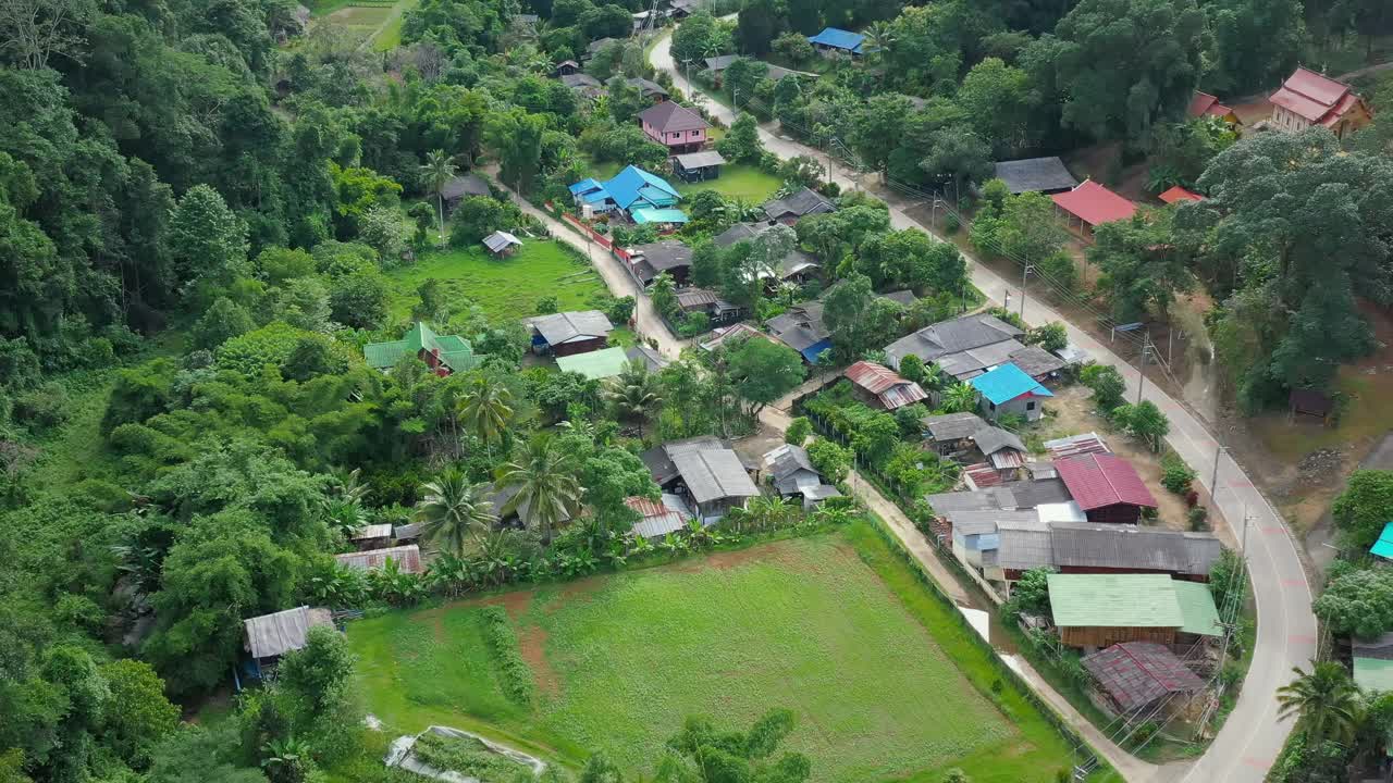 鸟瞰被群山环绕的村庄。无人机在泰国北部山区环绕的乡村城市上空飞行。视频素材