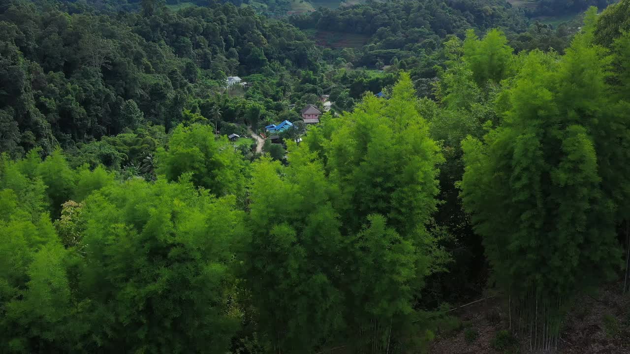 鸟瞰被群山环绕的村庄。无人机在泰国北部山区环绕的乡村城市上空飞行。视频素材