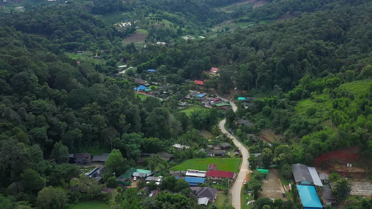 鸟瞰被群山环绕的村庄。无人机在泰国北部山区环绕的乡村城市上空飞行。视频素材