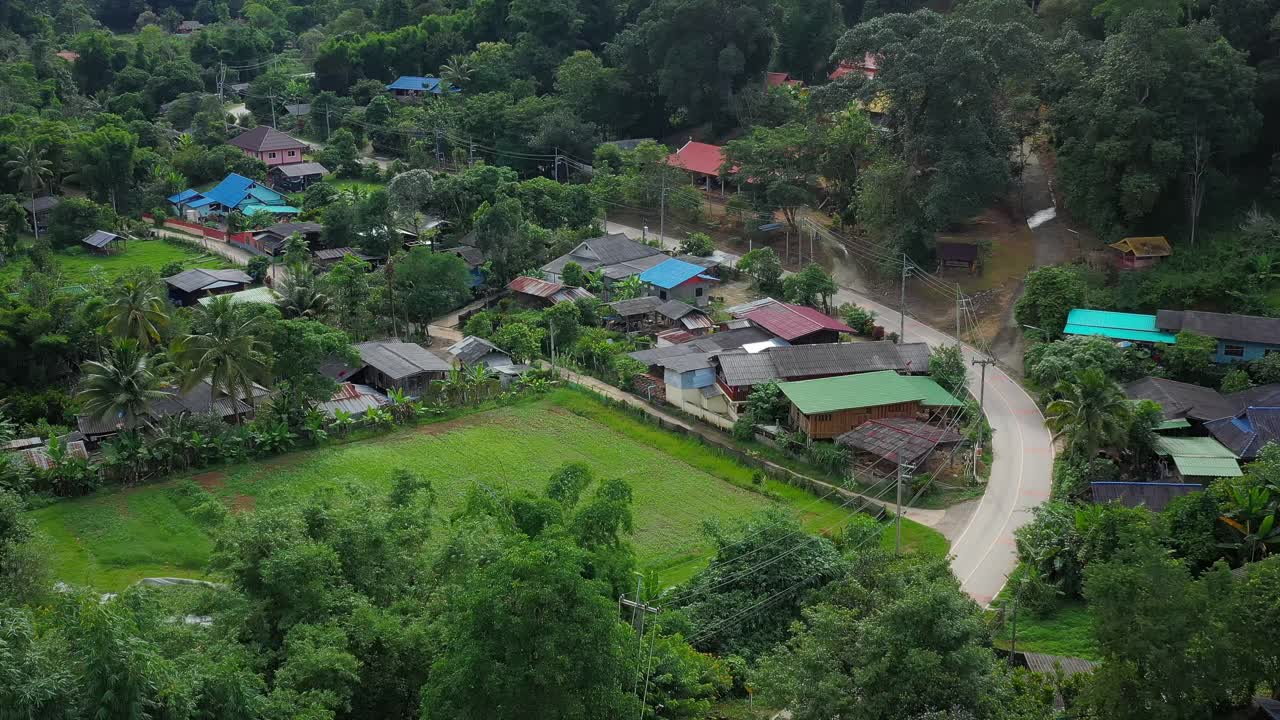 鸟瞰被群山环绕的村庄。无人机在泰国北部山区环绕的乡村城市上空飞行。视频素材