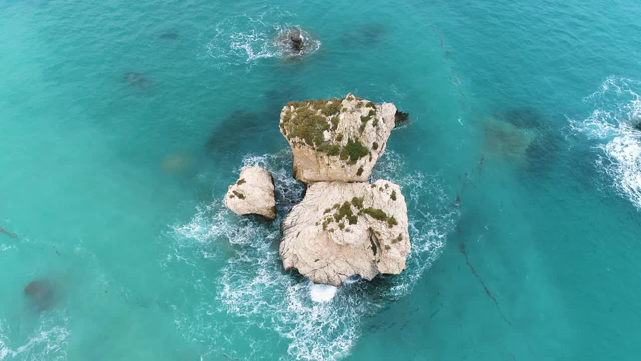 巨大的岩石在蓝色的海洋，海与蓝绿色的水和美丽的海滩。无人机4k拍摄。大海撞击孤山岩石，旅游胜地，度假休闲视频素材