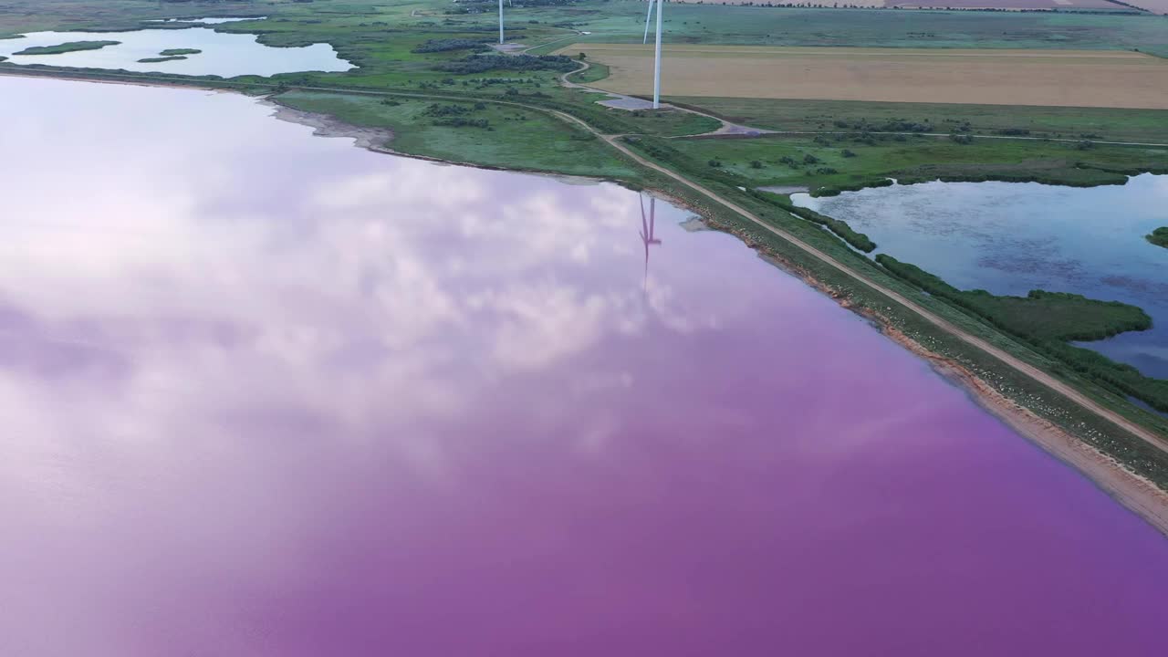 鸟瞰粉红湖。云层和风力涡轮机倒映在湖面上视频素材