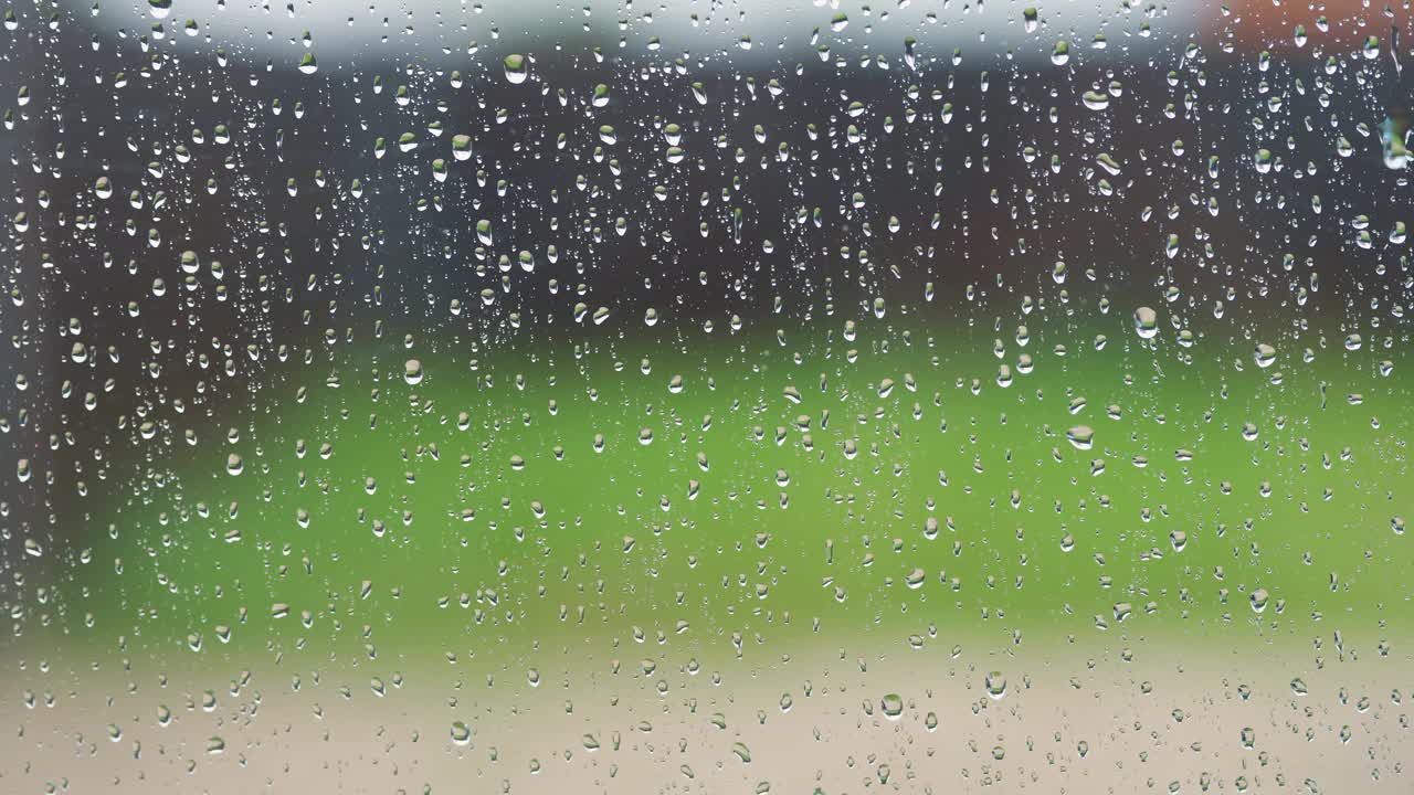 雨滴在窗口与模糊的背景。高质量的镜头，雨在窗口天空滴。夏天，雨水落在窗户玻璃上。雨滴，凝结在玻璃上，雨天，4K视频素材