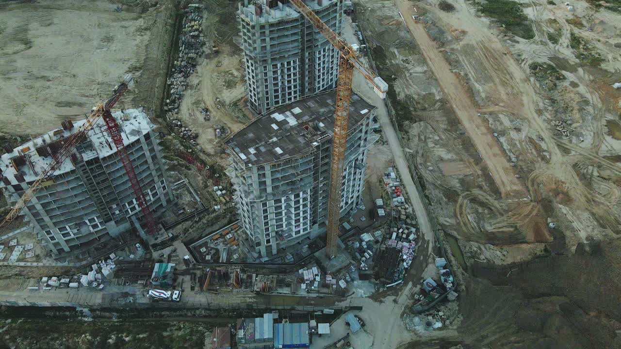 一个现代化城市街区的建筑工地。正在建设中的高层建筑。建筑塔式起重机。日落时的航空摄影。视频素材