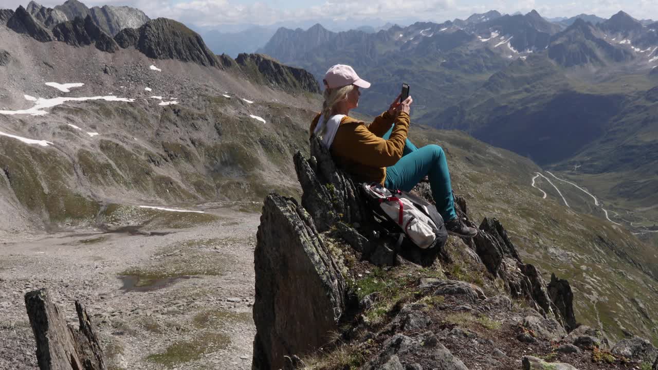 女徒步旅行者在山顶放松，用智能手机视频素材