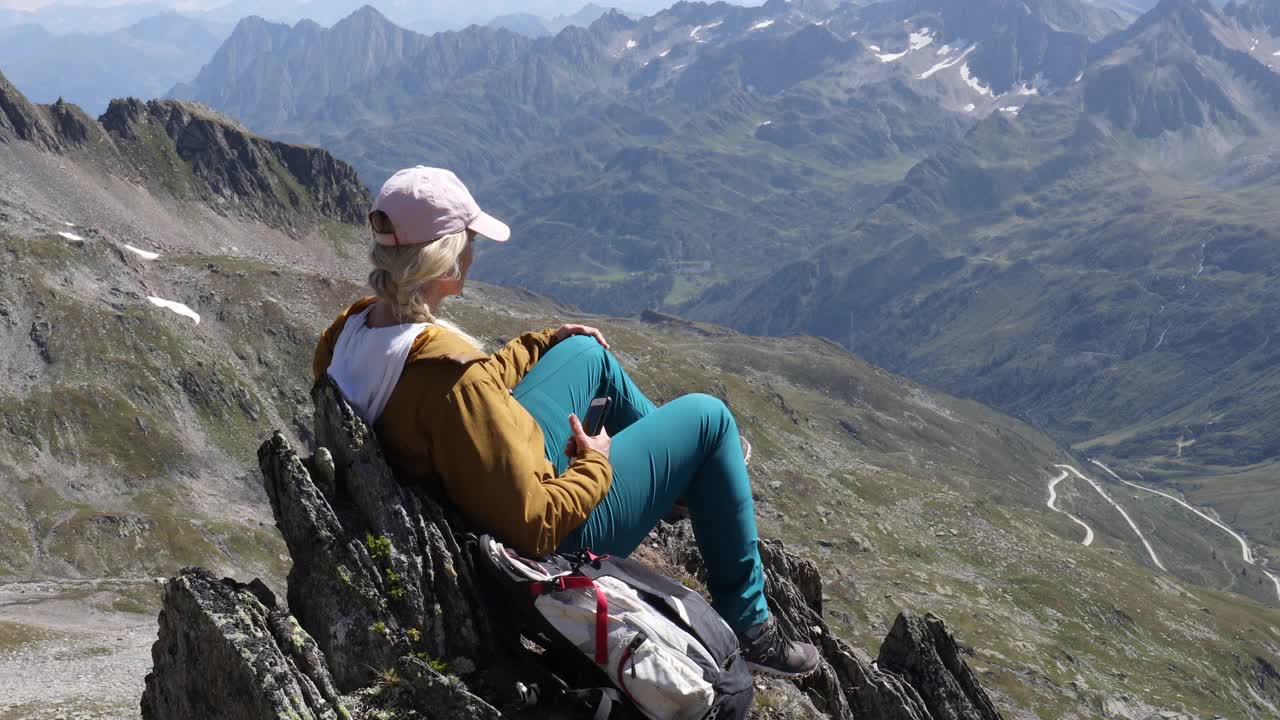 女徒步旅行者在山顶放松，用智能手机视频素材