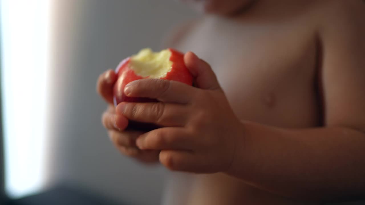 婴儿学步吃红苹果。孩子吃健康零食视频素材