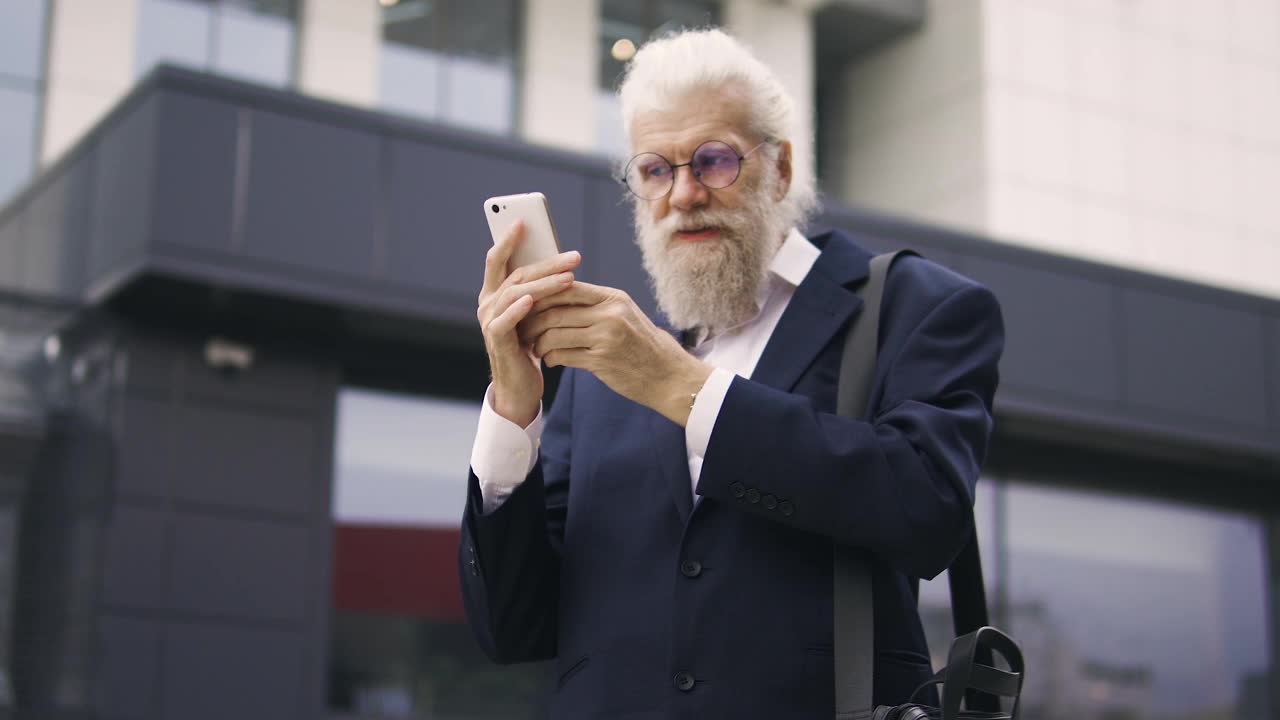 正成熟的男人正在调整胡子，看着智能手机显示屏上的倒影视频素材