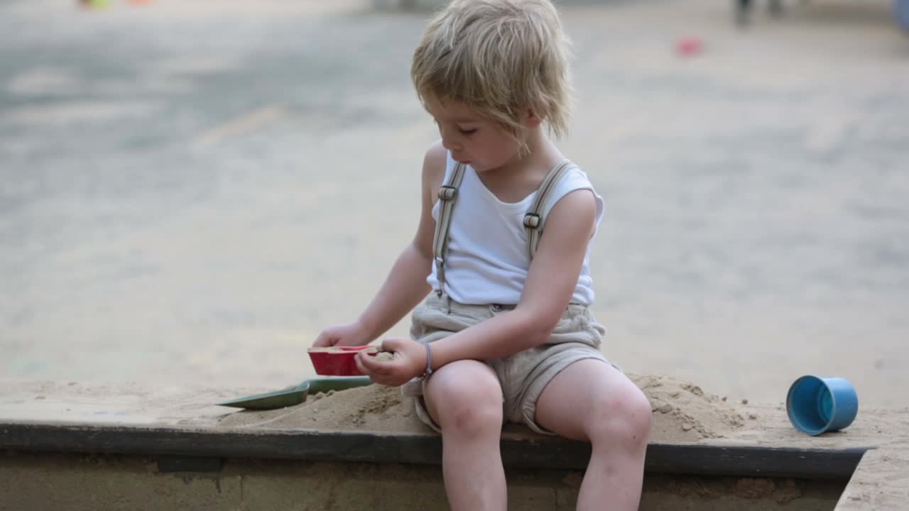 可爱的小孩，金发男孩，在公园的沙坑里玩视频素材