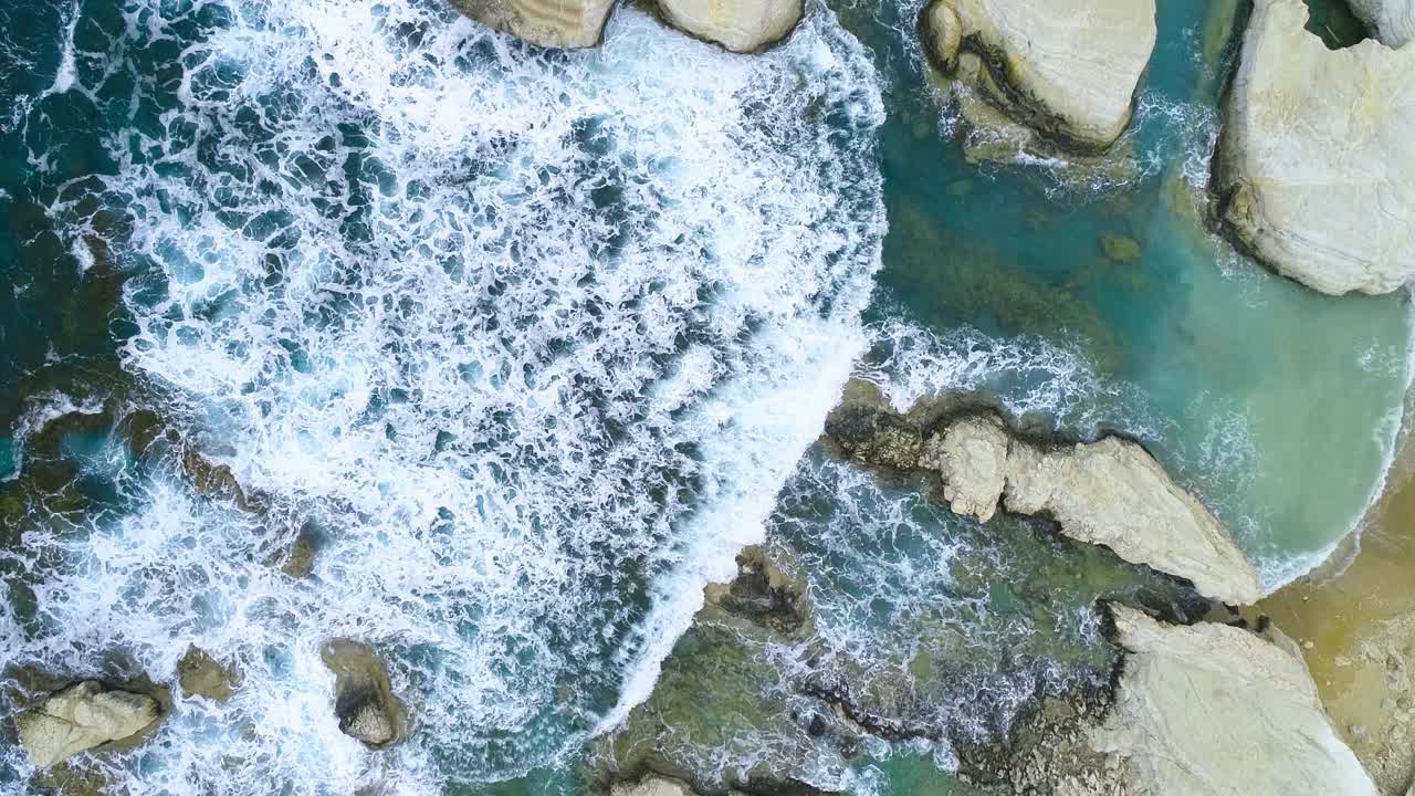 迷人的崎岖的海滩在塞浦路斯，一个地质奇迹，海浪飞溅的海滩与岩石。美丽的背景，海中的悬崖，4k顶部鸟瞰图视频素材