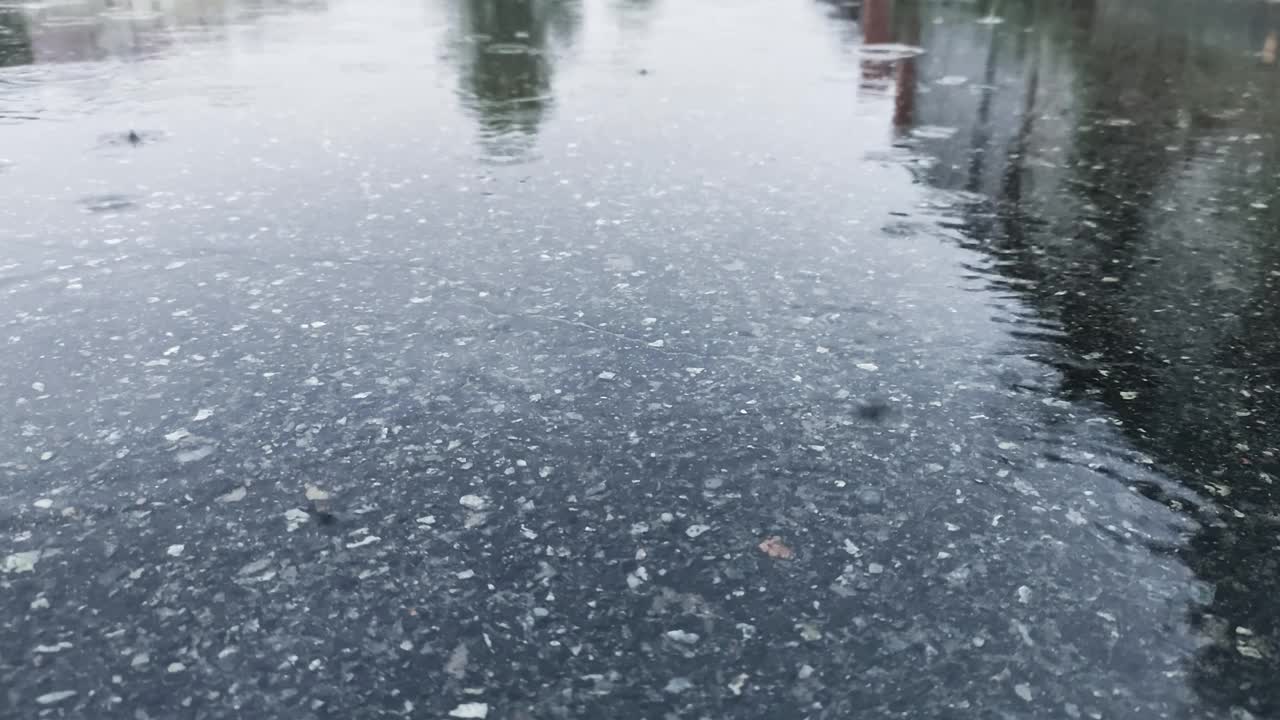 风平浪静的雨天，水滴落进水坑里，形成小气泡。视频素材