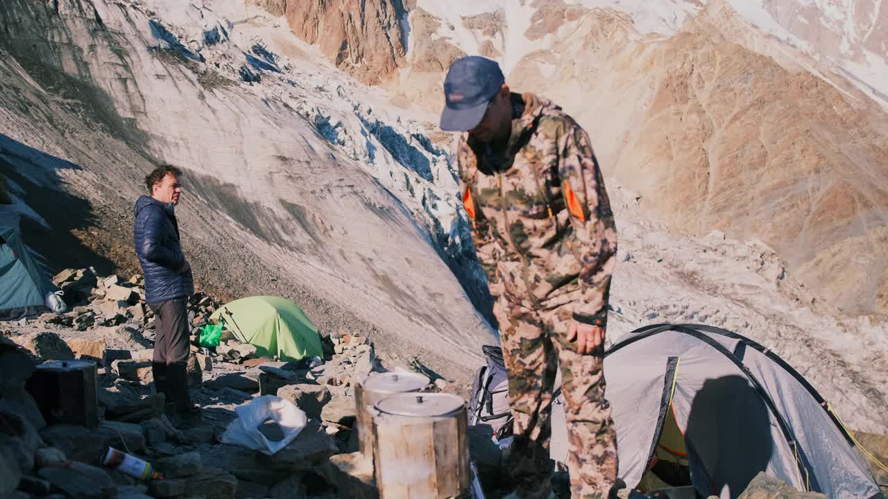 在登山营地，一名男子打开锅里煮熟的食物的盖子。视频素材