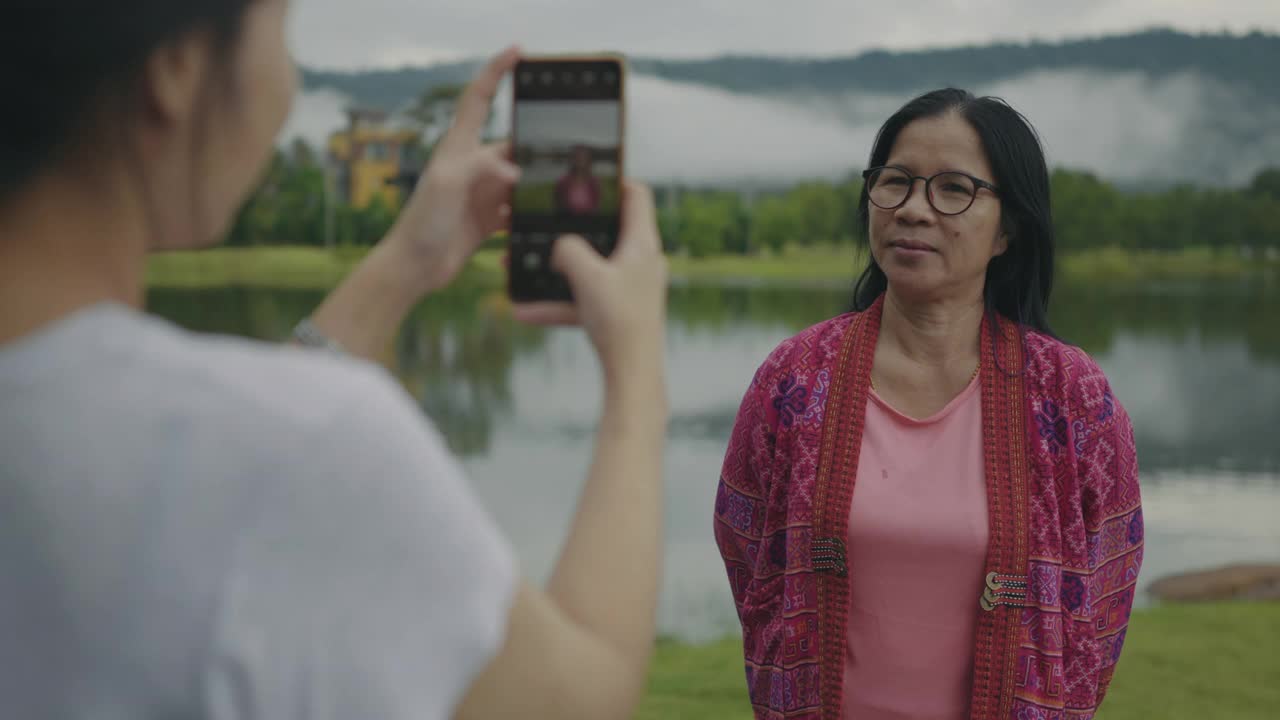 一个女儿给她的母亲拍了一张美丽的湖和雨林山的照片。视频下载