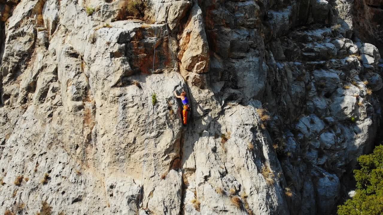 鸟瞰图的女性高山攀岩者正在攀登一座小山的顶峰视频素材画面1