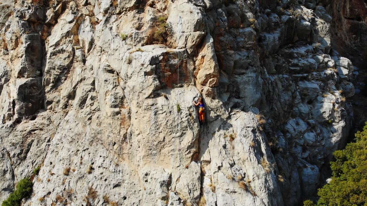 鸟瞰图的女性高山攀岩者正在攀登一座小山的顶峰视频素材画面2