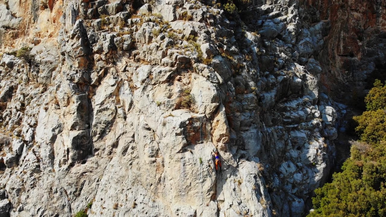 鸟瞰图的女性高山攀岩者正在攀登一座小山的顶峰视频素材画面4
