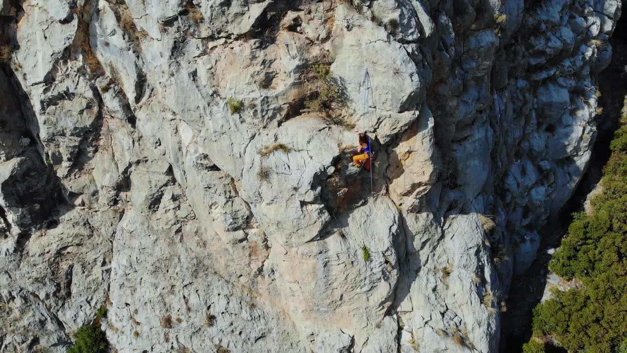 鸟瞰图的女性高山攀岩者正在攀登一座小山的顶峰视频素材画面1