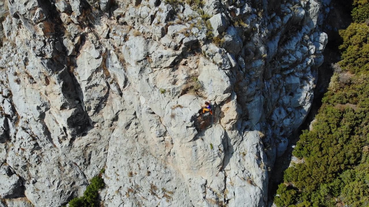 鸟瞰图的女性高山攀岩者正在攀登一座小山的顶峰视频素材画面2