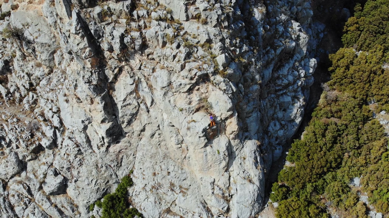 鸟瞰图的女性高山攀岩者正在攀登一座小山的顶峰视频素材画面3
