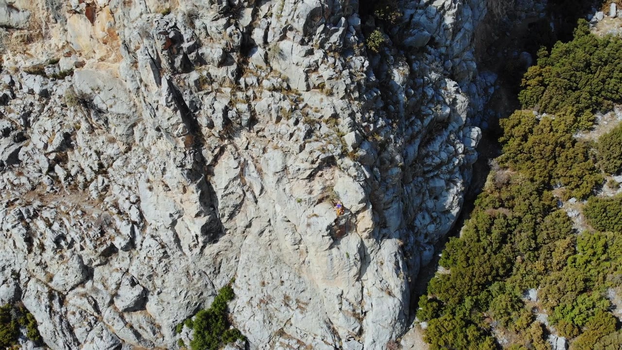 鸟瞰图的女性高山攀岩者正在攀登一座小山的顶峰视频素材画面4