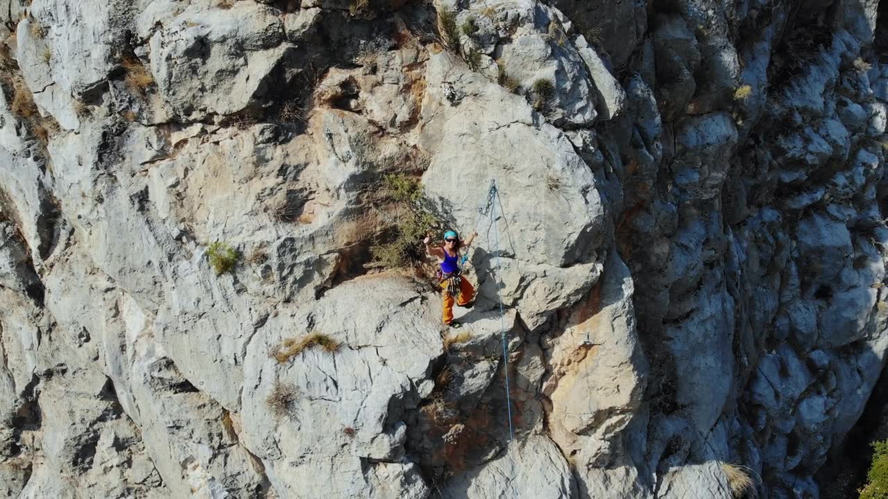 鸟瞰图的女性高山攀岩者正在攀登一座小山的顶峰视频素材画面1