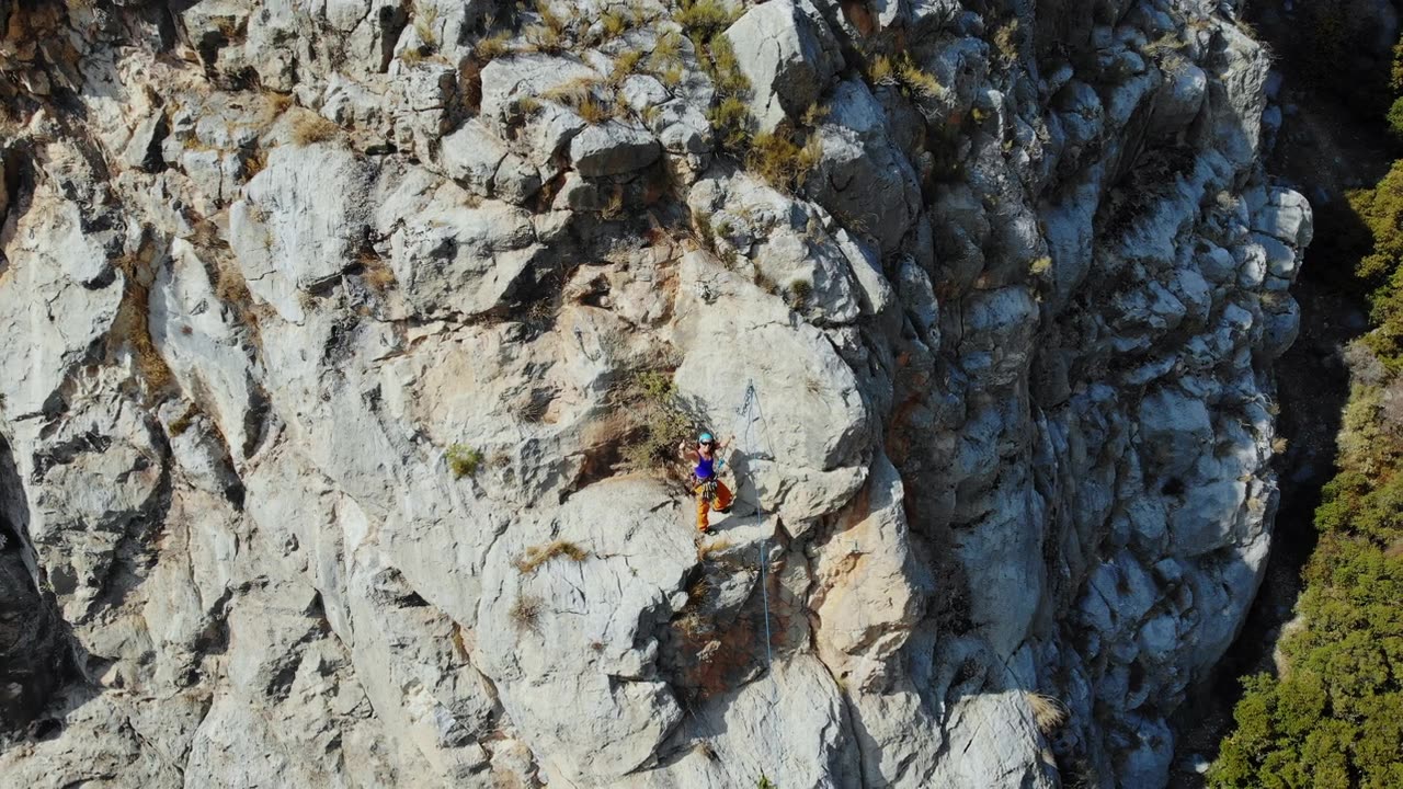 鸟瞰图的女性高山攀岩者正在攀登一座小山的顶峰视频素材画面2