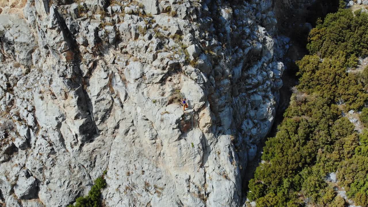 鸟瞰图的女性高山攀岩者正在攀登一座小山的顶峰视频素材画面1