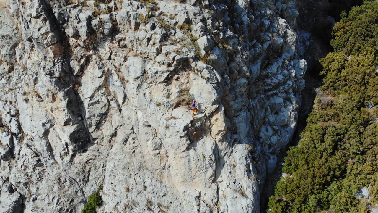 鸟瞰图的女性高山攀岩者正在攀登一座小山的顶峰视频素材画面2