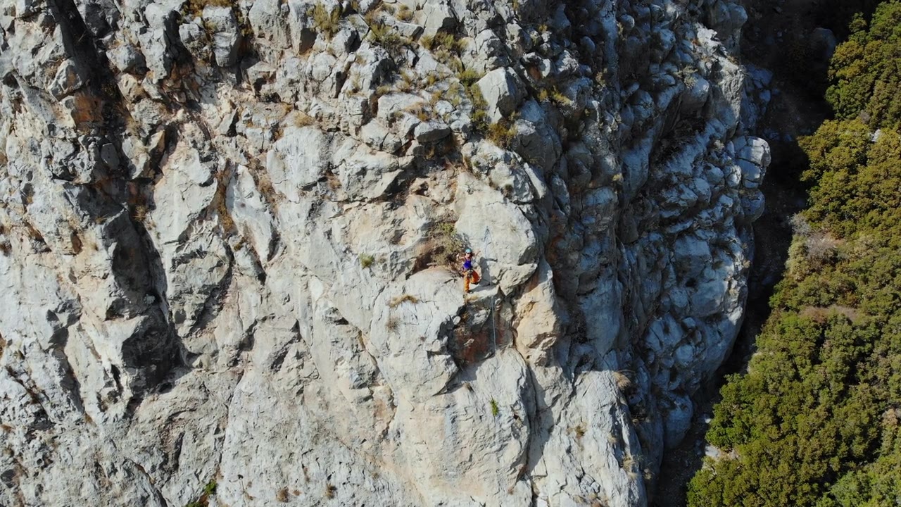鸟瞰图的女性高山攀岩者正在攀登一座小山的顶峰视频素材画面3