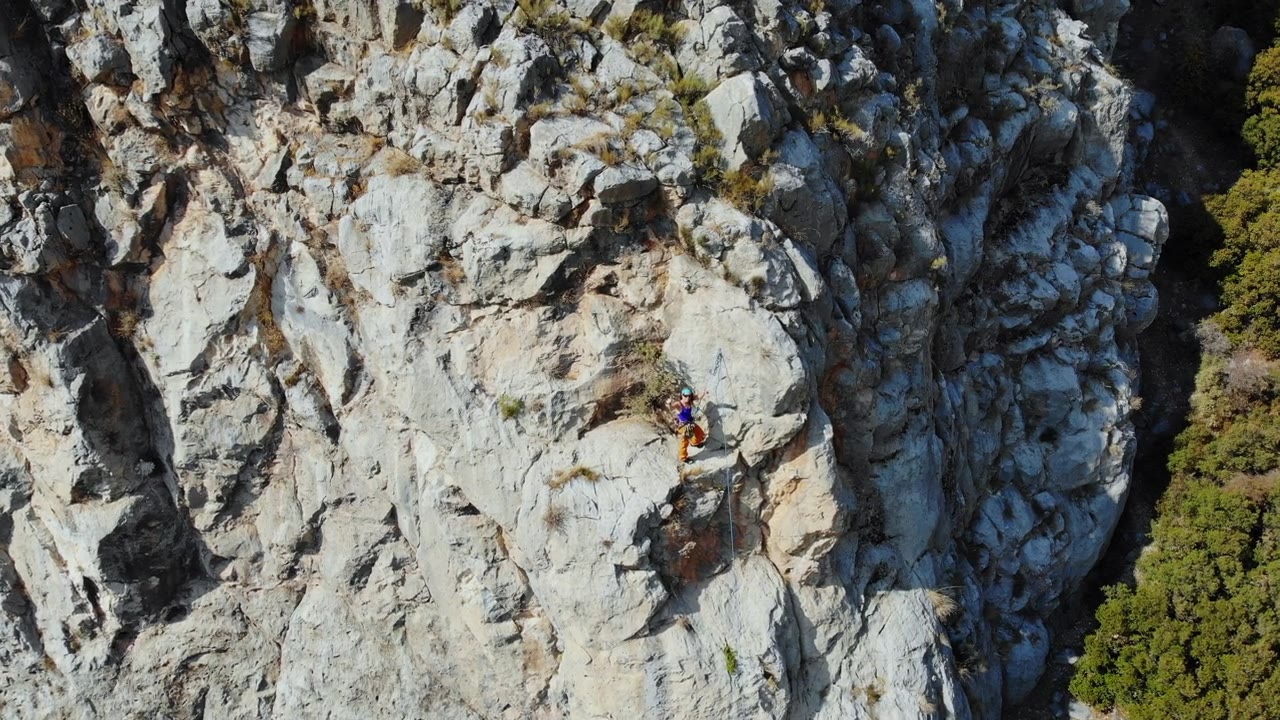 鸟瞰图的女性高山攀岩者正在攀登一座小山的顶峰视频素材画面4