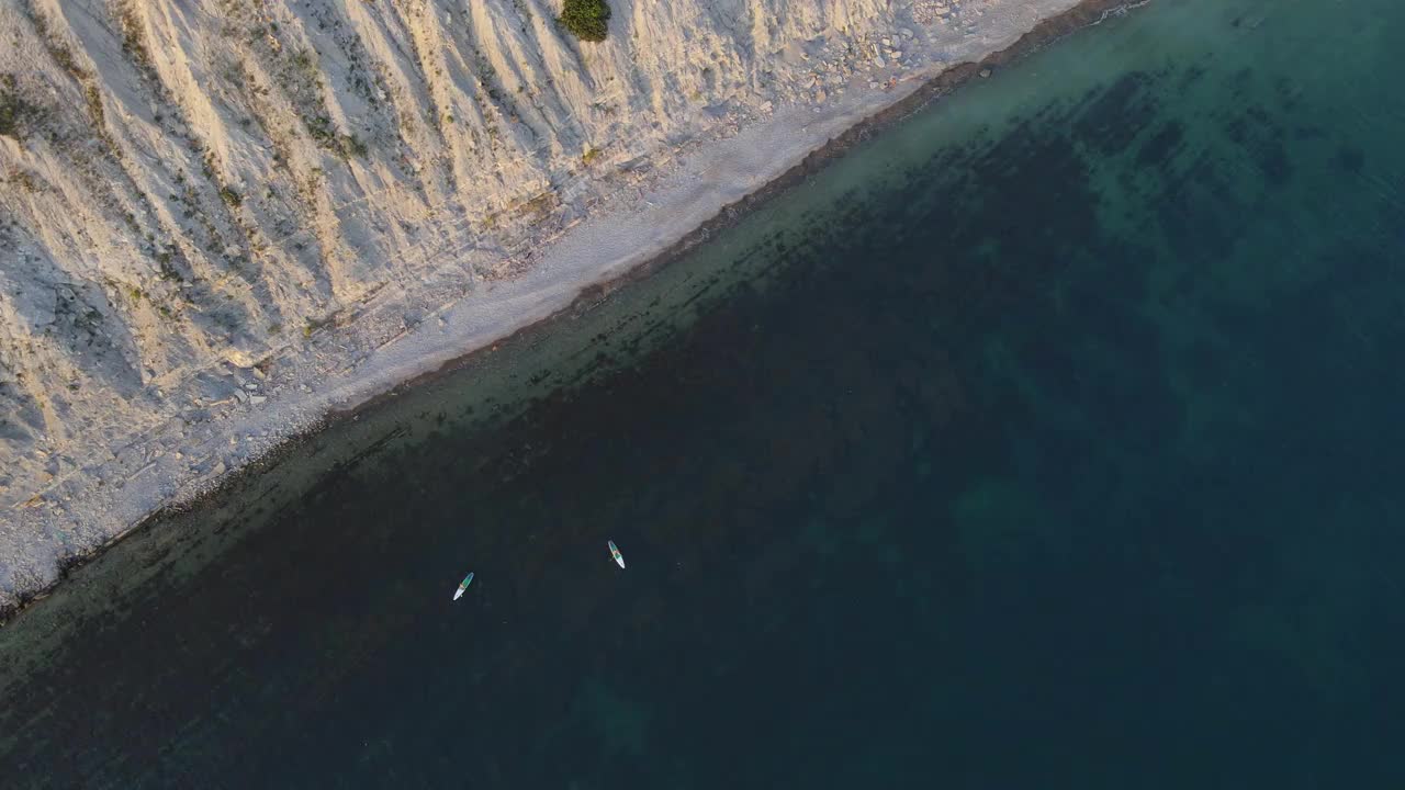 旅行者在海上站桨板。在透明的大海里，人们在红色的帆板上划桨。鸟瞰图视频素材