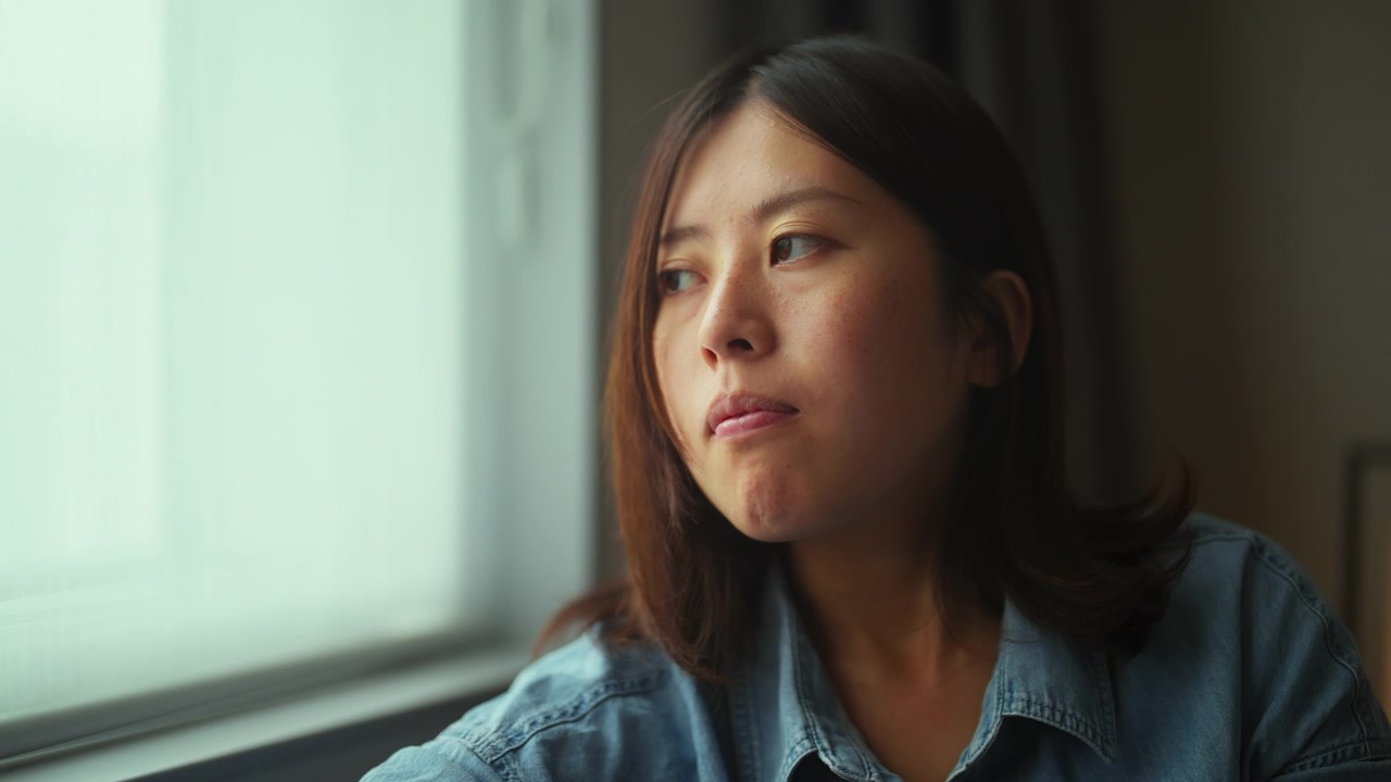 年轻女子坐在靠窗的沙发上，用着智能手机回家视频素材画面4