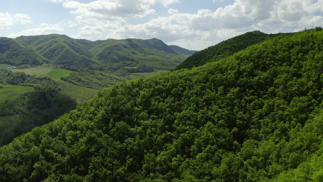 空中田园诗的自然岩层对多云的天空，无人机飞行向前在绿色森林-亚平宁山脉，意大利视频素材