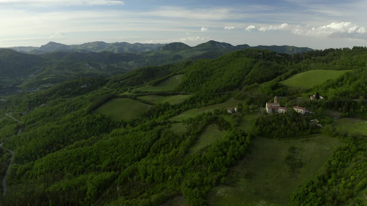 绿色山丘上建造的住宅的航拍，无人机在景观上方飞行-意大利亚平宁山脉视频素材