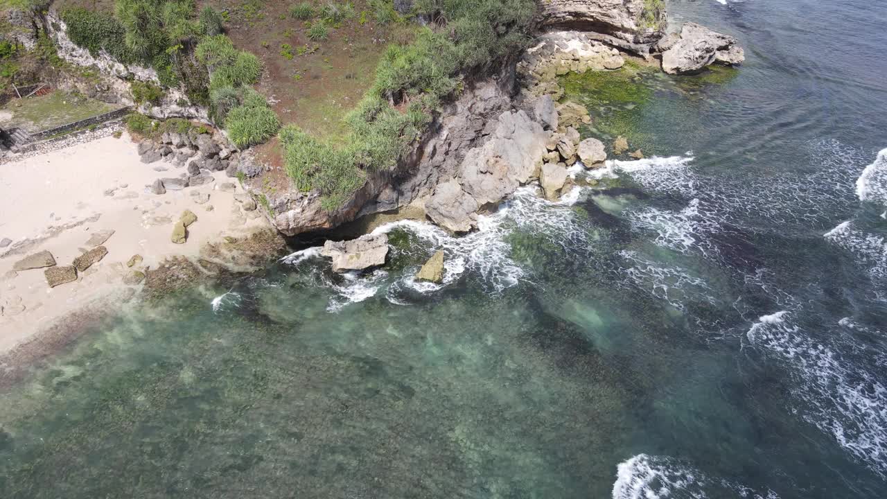 鸟瞰图海浪打破岩石在蓝色的海洋。海浪在美丽的海滩鸟瞰图无人机4k拍摄。视频素材