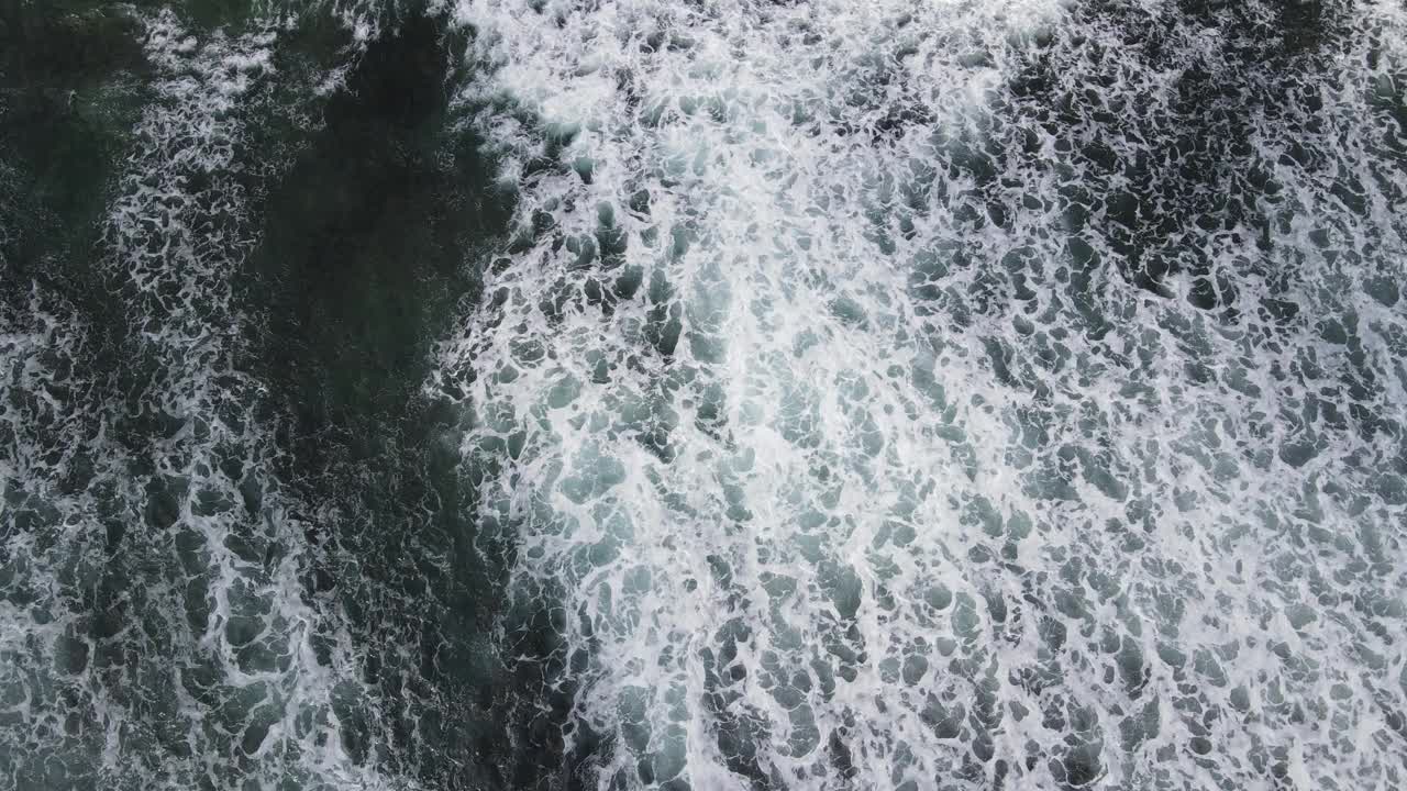 鸟瞰图海浪打破岩石在蓝色的海洋。海浪在美丽的海滩鸟瞰图无人机4k拍摄。视频素材